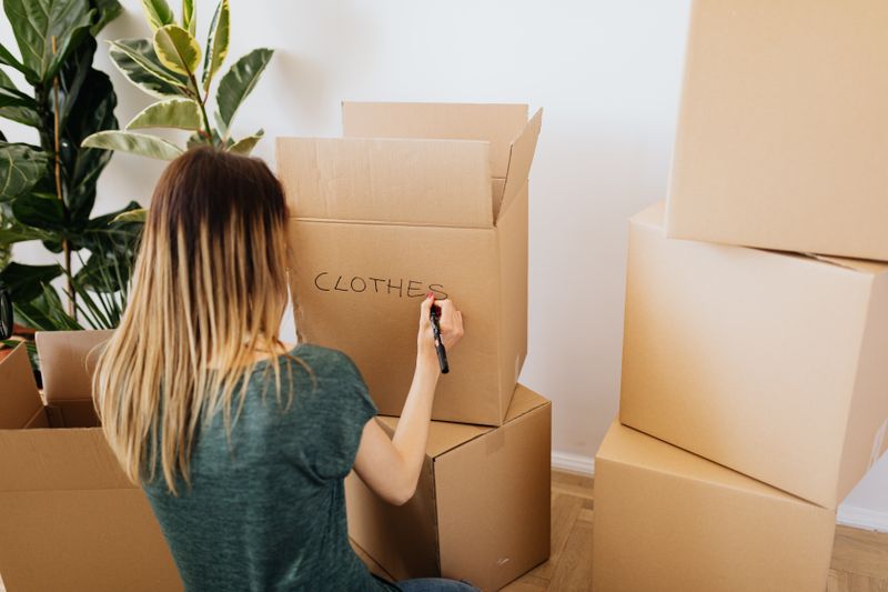Hand labeling a moving box with the word clothes